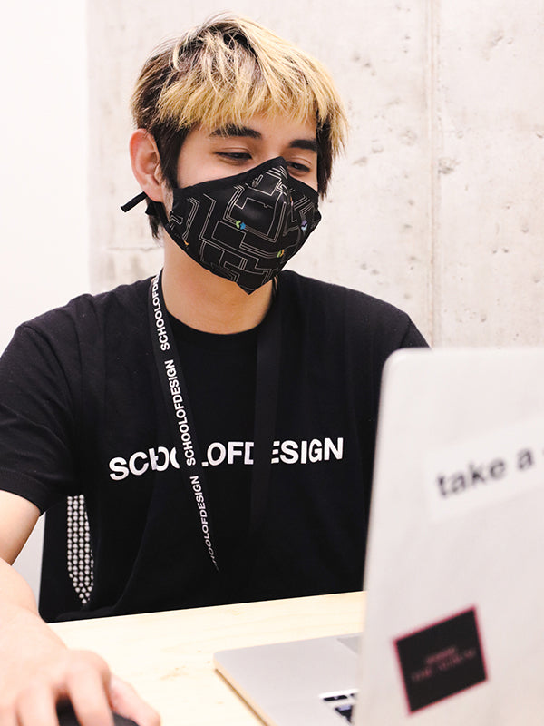 black mask with mostly white circuit board pattern; worn by model