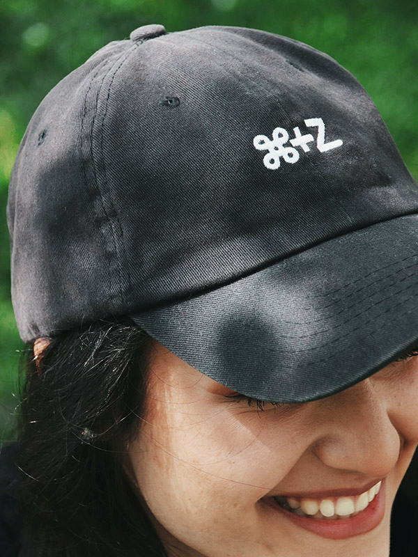close up of a girl smiling wearing the 100% cotton black ball cap with command z shortcode embroidered in white
