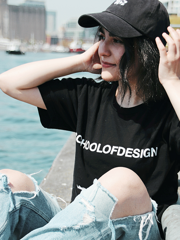 girl sitting down wearing school of design black cotton t shirt