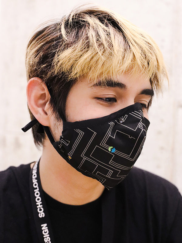 black mask with mostly white circuit board pattern; worn by model