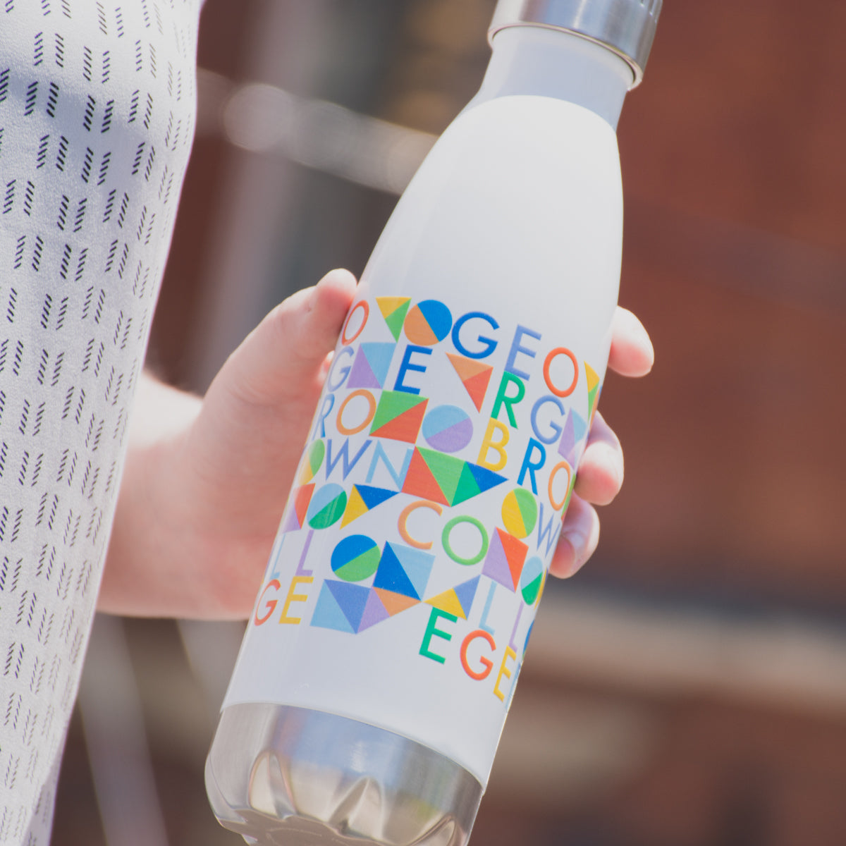 close up of white stainless steel water bottle with george brown college multicoloured text design