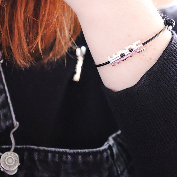silver 'hope' bracelet and necklace worn by person in black