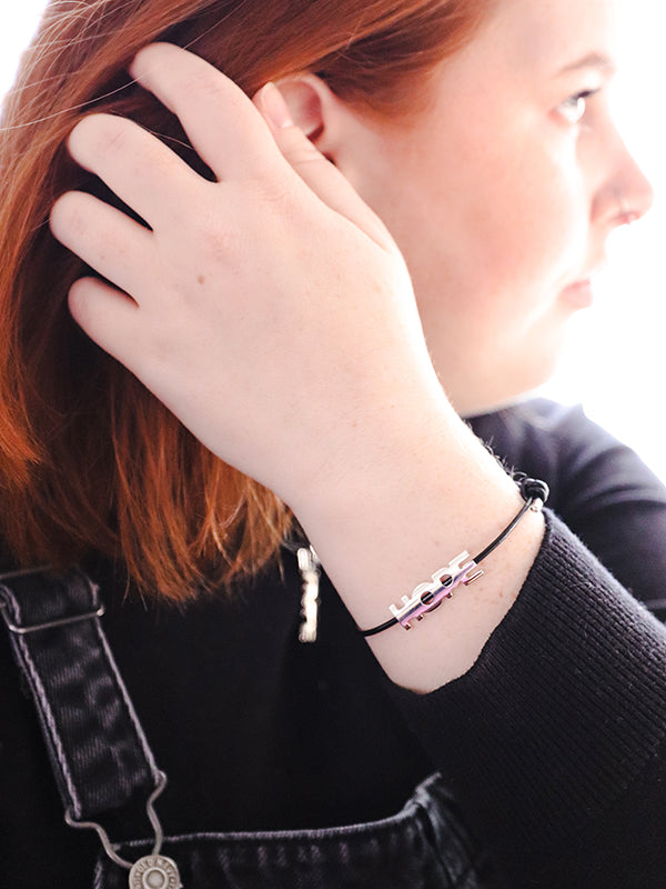 silver 'hope' bracelet and necklace worn by person in black