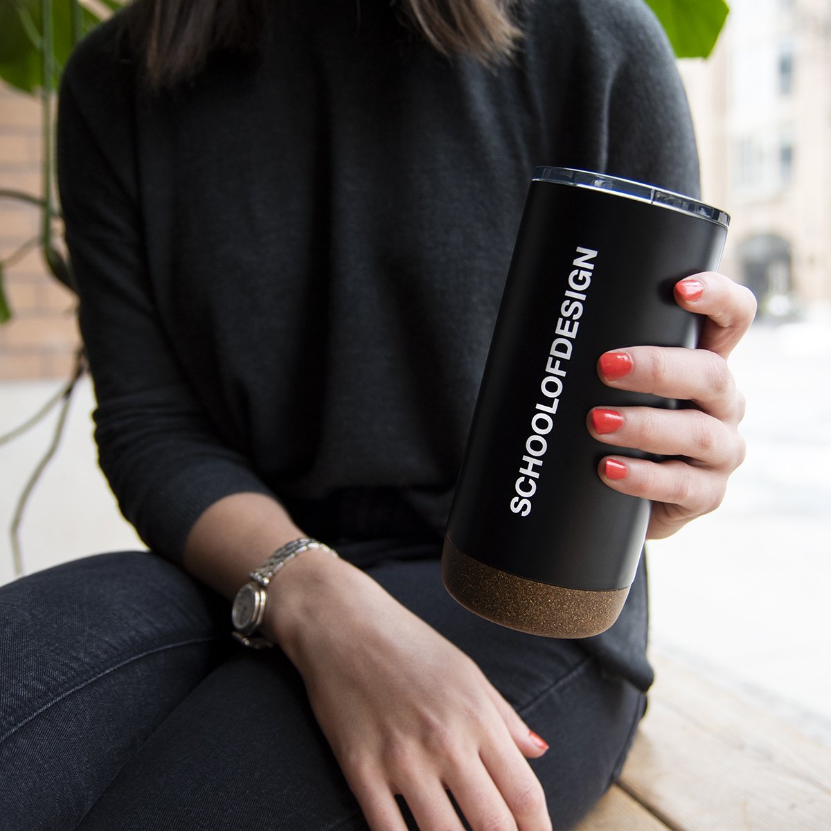 girl holding black school of design travel mug with white text 