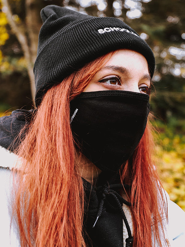 Person with red hair wearing black School of Design toque and black School of Design mask