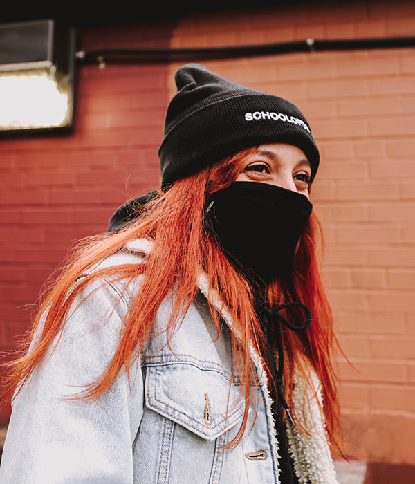 Person with red hair wearing black School of Design toque and black School of Design mask
