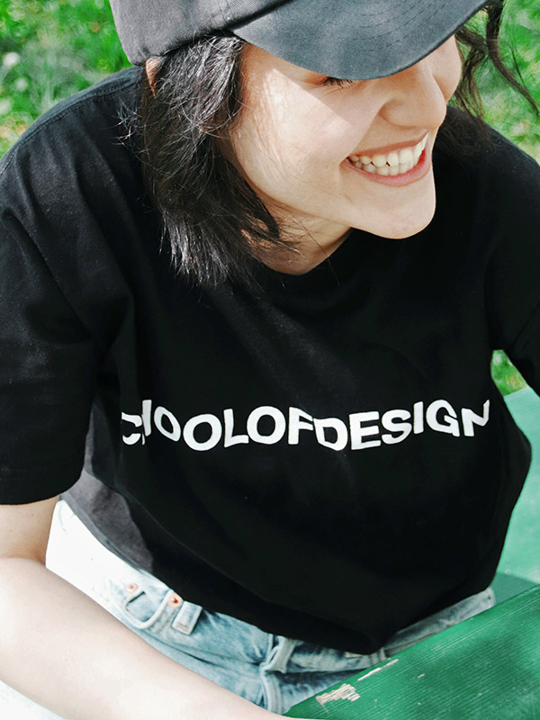 girl smiling sitting down wearing school of design black cotton t shirt