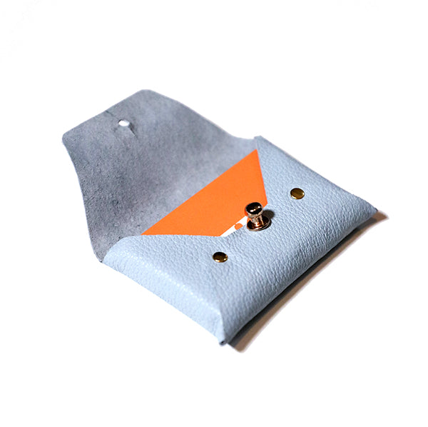 blue, rectangular leather card holder, open. Orange business cards inside