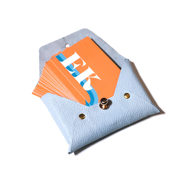 blue, rectangular leather card holder. Orange business cards spilling out.