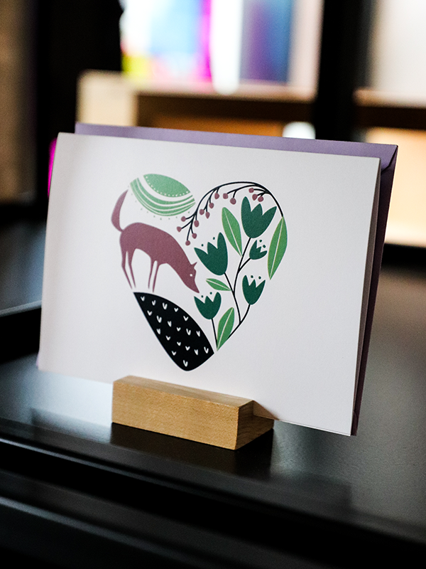 forest elements (fox, leaves, flowers) contained in a heart shape on a white card