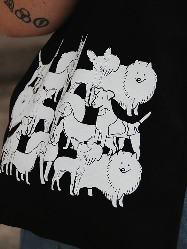 close up of 14 x 15" 100% cotton black tote with several illustrations of different dog breeds mixed together in white