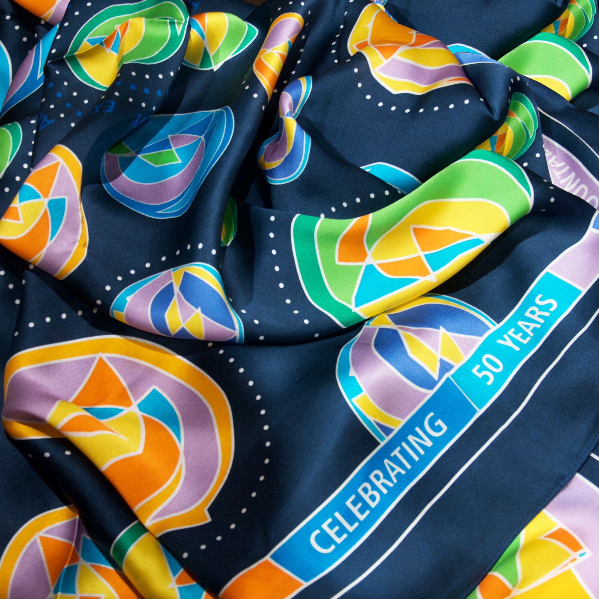close up of GBC 50th Pathways Silk Scarf, showing the celebrating 50 years text